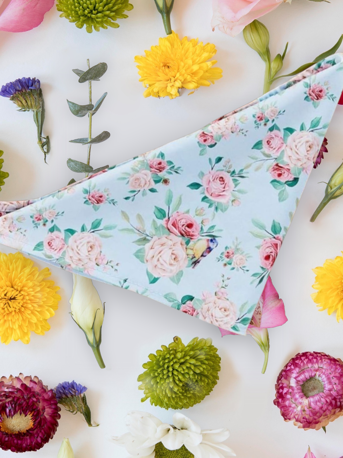 dog bandana with floral design laid out with flowers around it