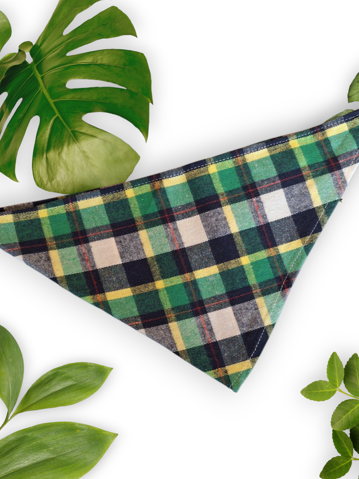 A green plaid neck tie bandana for dogs, displayed on a white background with leaves around it.
