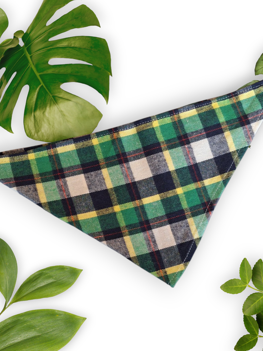 A green plaid neck tie bandana for dogs, displayed on a white background with leaves around it.