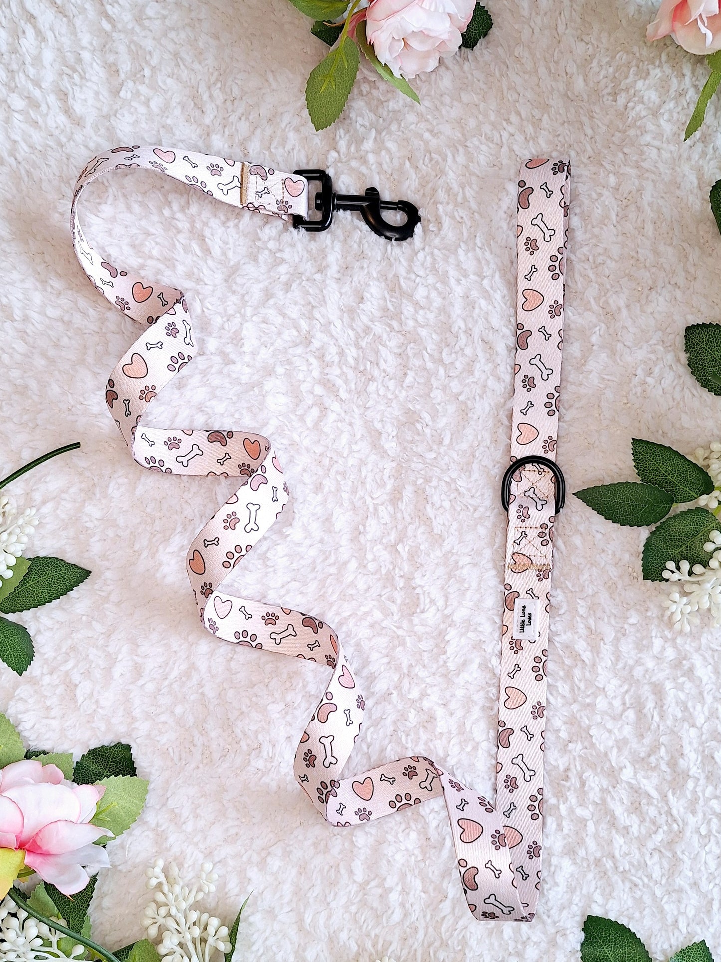 A floral patterned dog lead laid out on a white surface, with a D ring and swivel back clip.