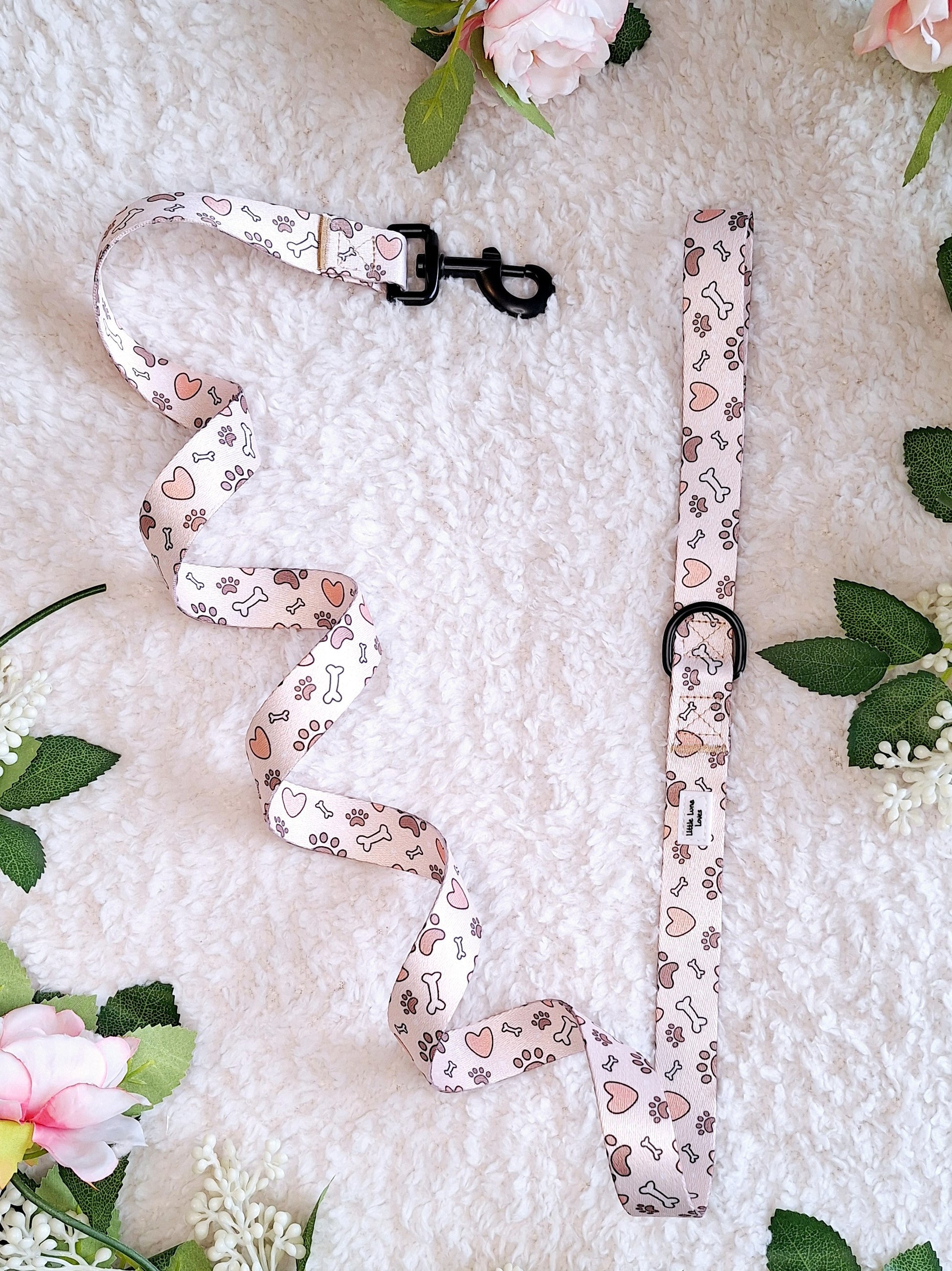A floral patterned dog lead laid out on a white surface, with a D ring and swivel back clip.