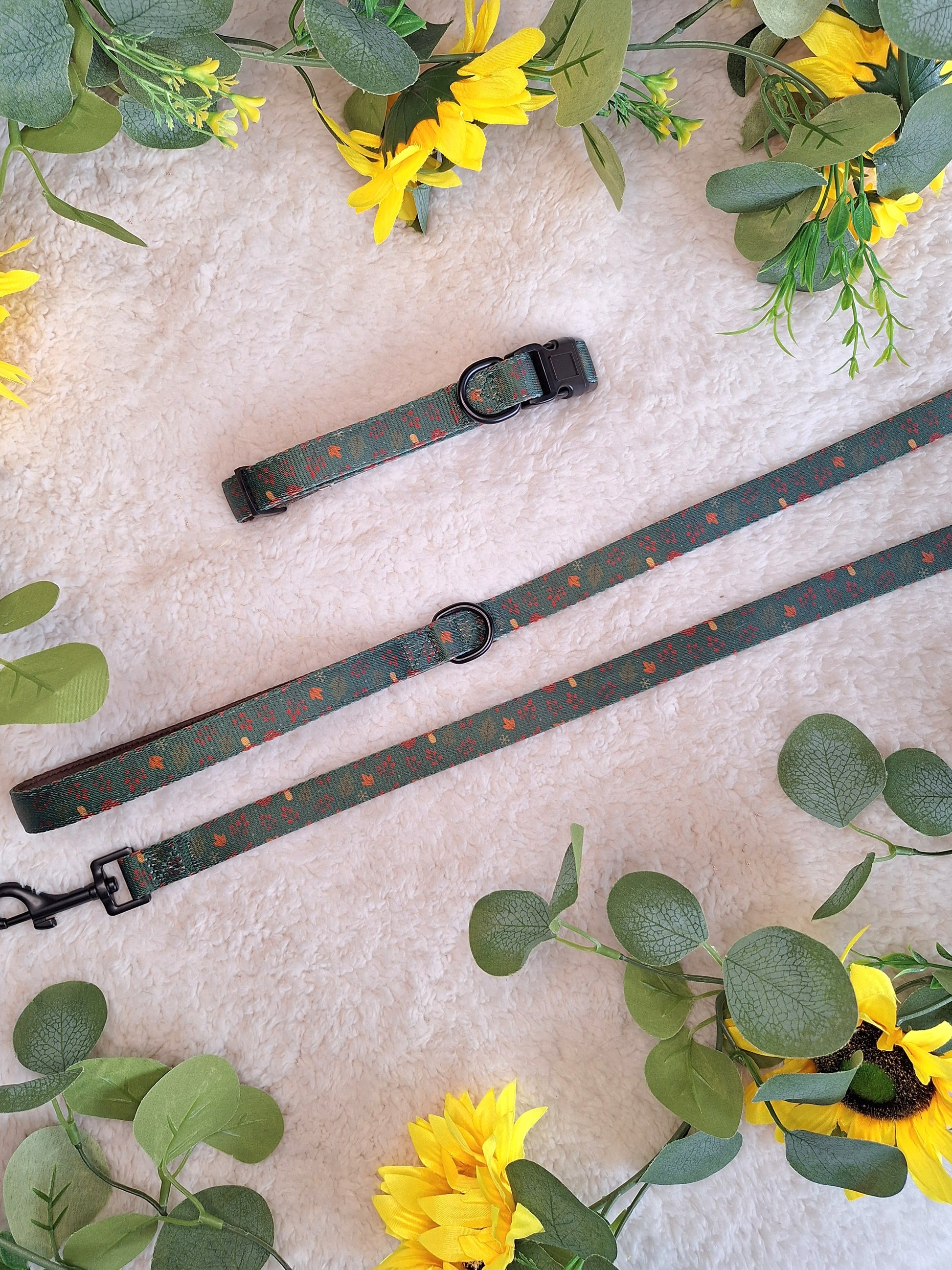 Dog lead & collar with floral and green leaf decorations on a light surface.
