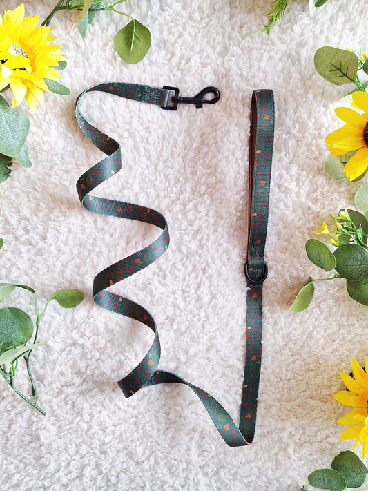 Green dog lead with leaf design, laid on white background with sunflowers