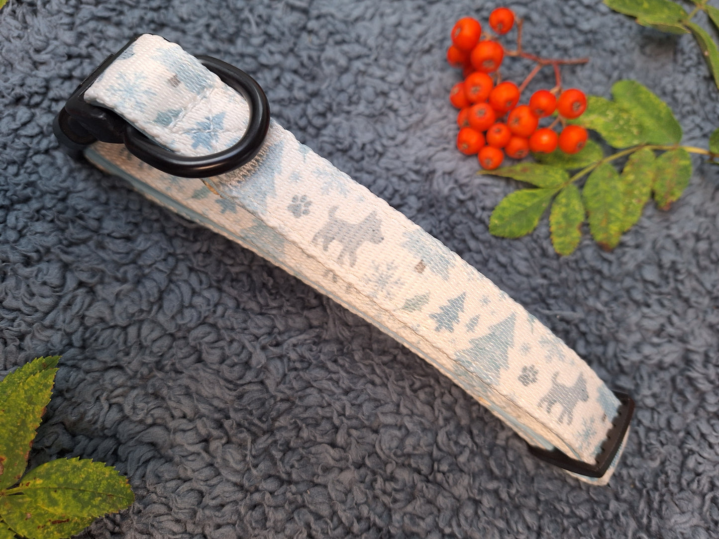 Dog collar with winter pattern on a textured surface with berries and leaves.